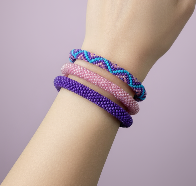 Colorful beaded bracelets on a wrist against a light purple background - Beadzy