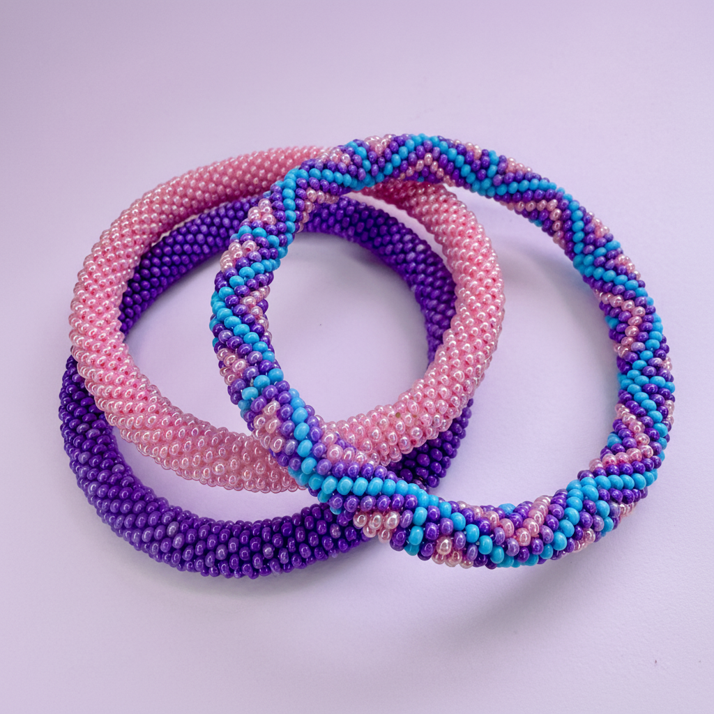 Three beaded hair ties in pink, purple, and blue on a light purple background - Beadzy
