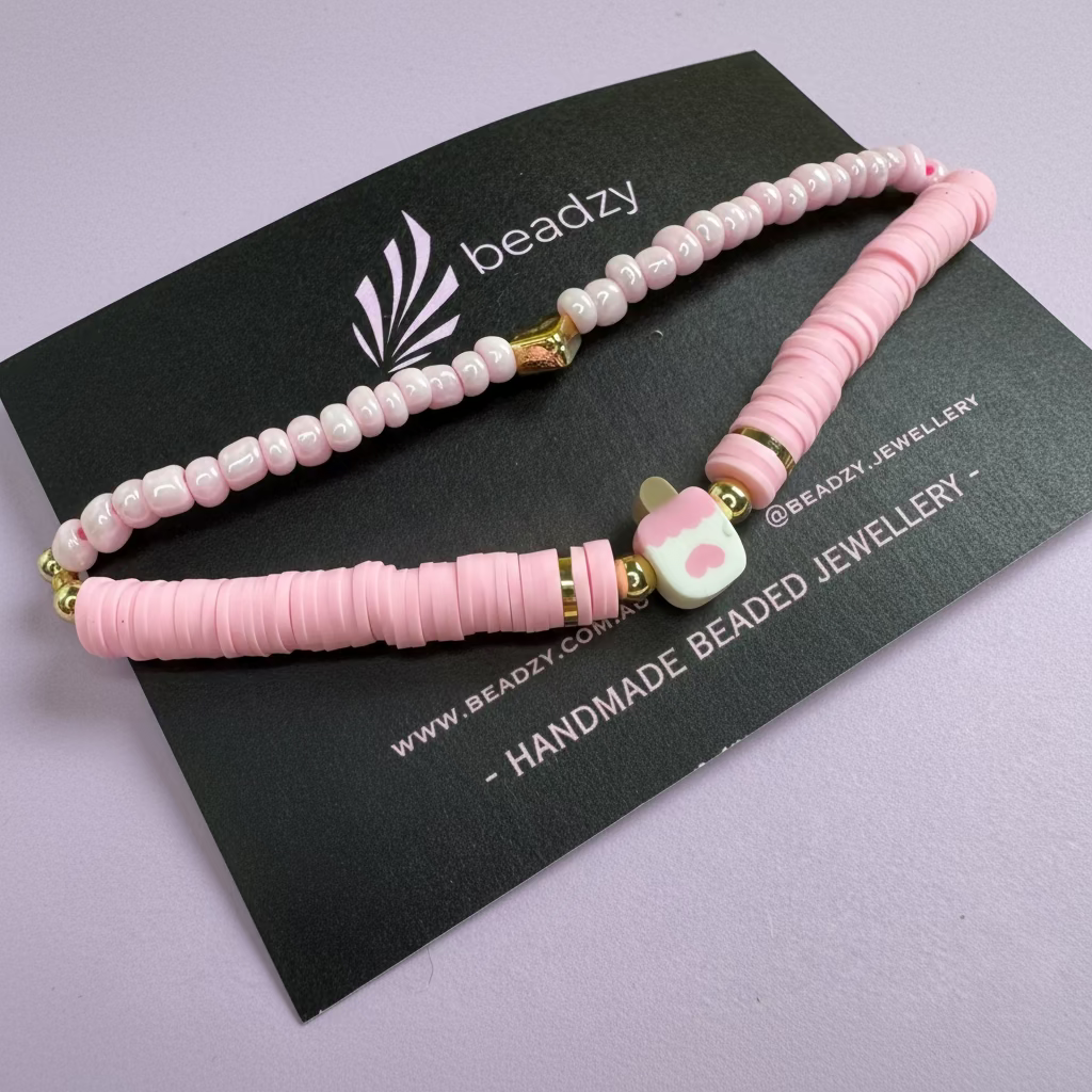 Two pink beaded bracelets on a black card with 'beadzy' branding against a yellow background. - Beadzy