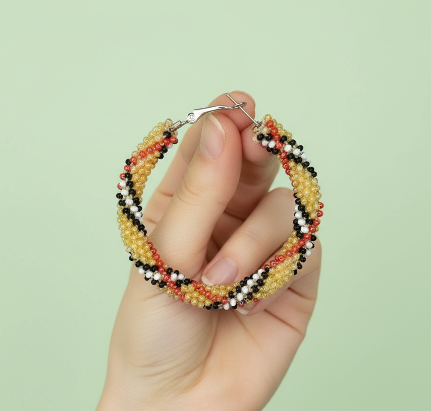 Hand holding a beaded hoop earring against a light green background - Beadzy