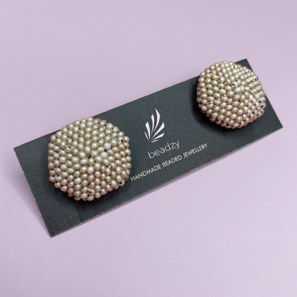 Pearl earrings on a 'beadzy' branded card against a light purple background - Beadzy