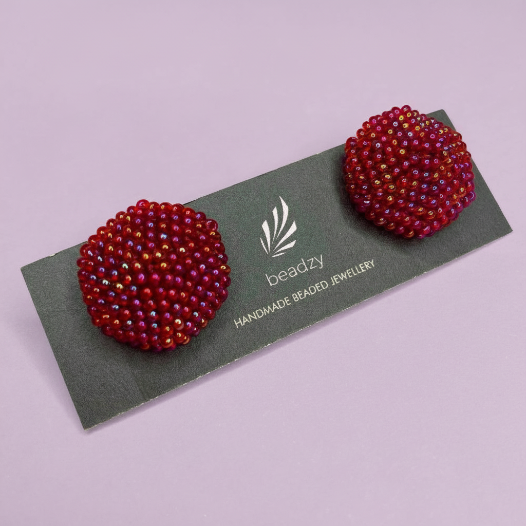 Pair of red beaded earrings on a green card with 'beadzy' branding against a light purple background. - Beadzy