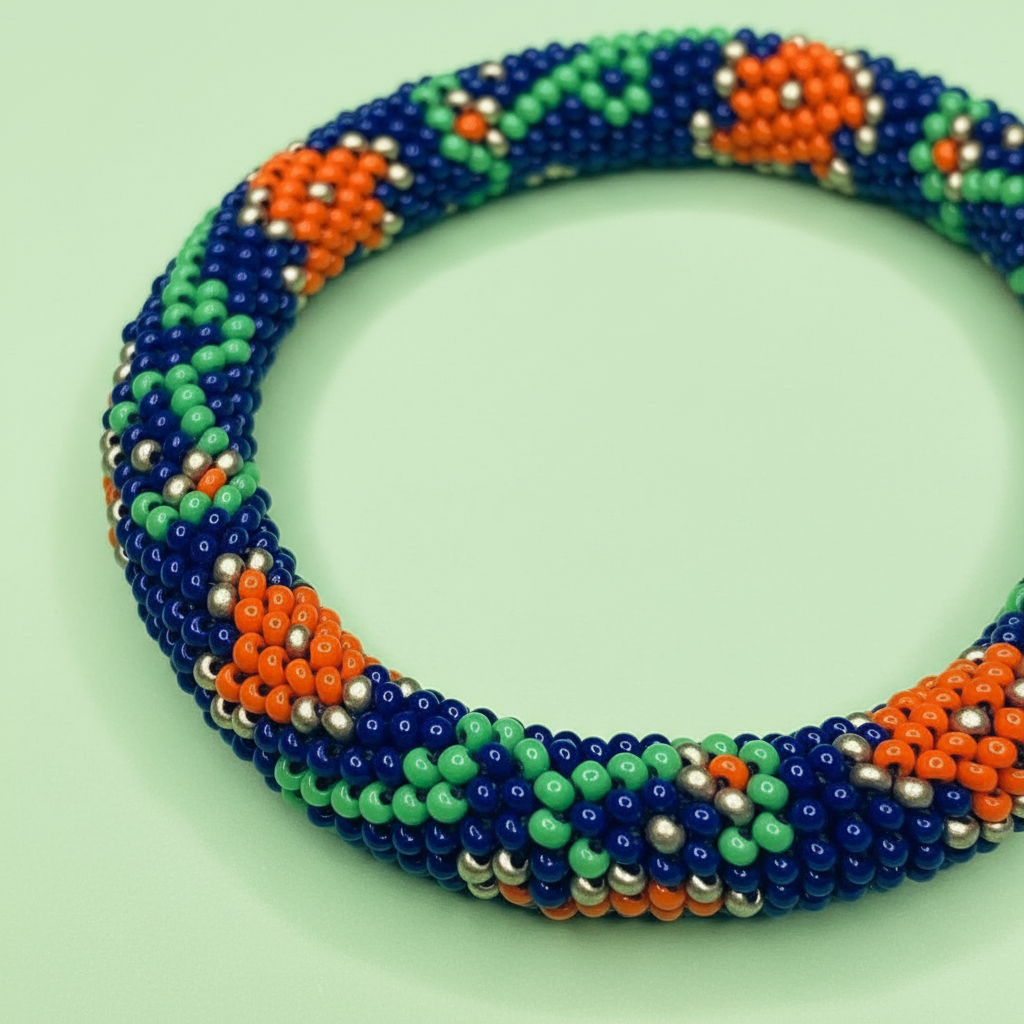 Colorful beaded bracelet with blue, green, orange, and silver beads on a light green background - Beadzy