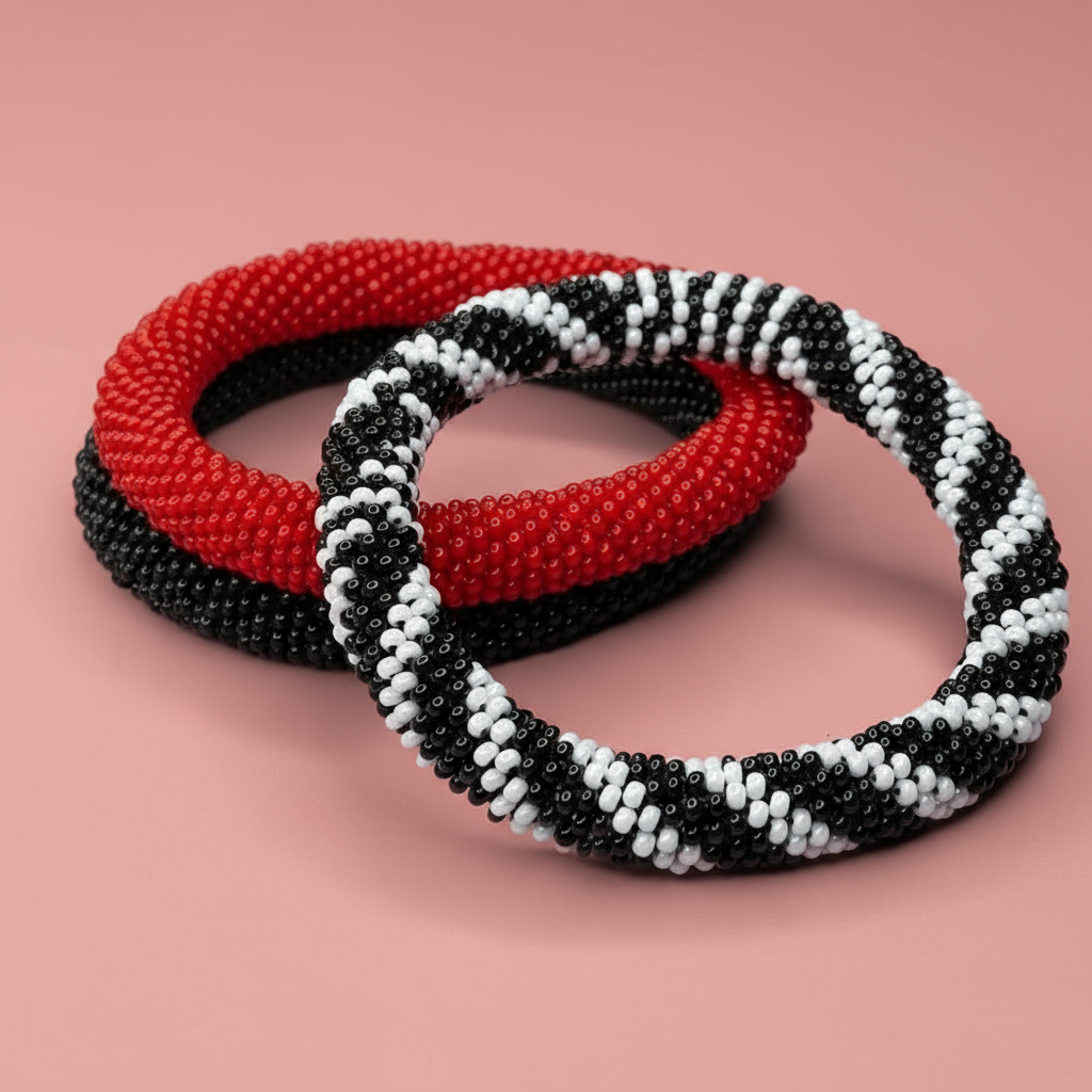 Three beaded bracelets, one red one black, one black and white, on a pink background - Beadzy