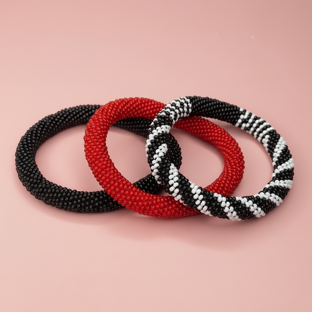 Three beaded bracelets in black, red, and a pattern of black, white, and red on a pink background. - Beadzy