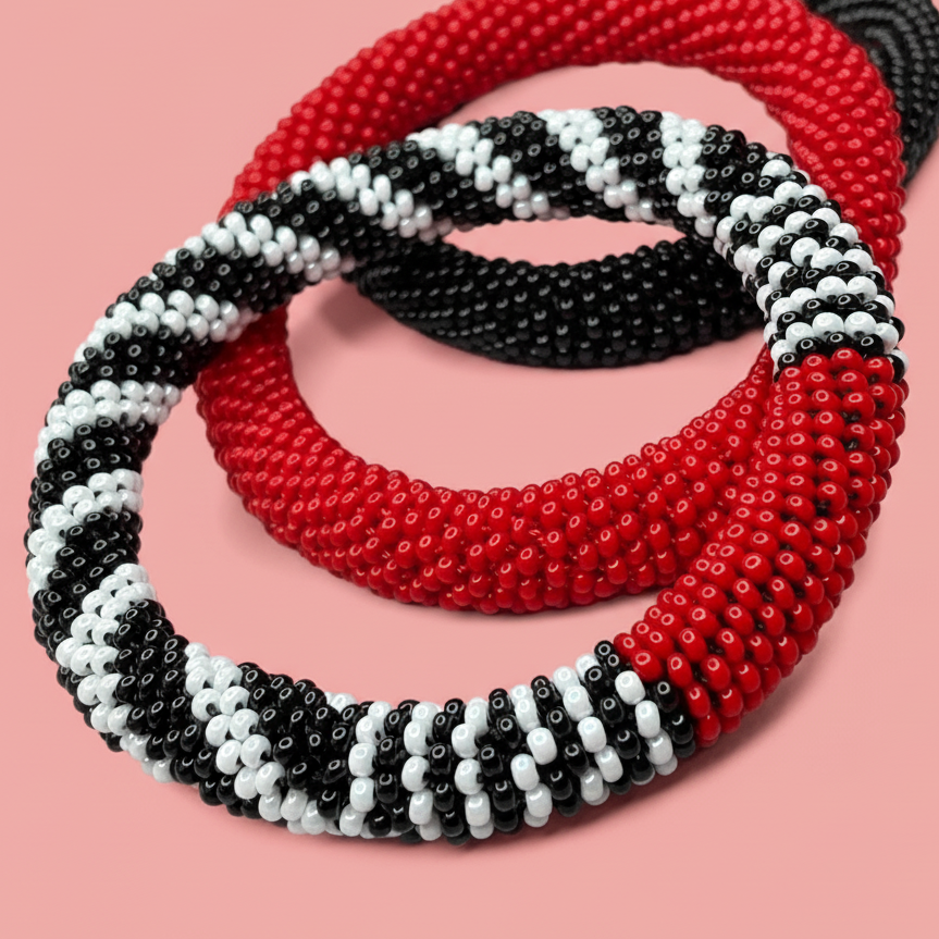 Three beaded bracelets in red, black, and white on a pink background - Beadzy