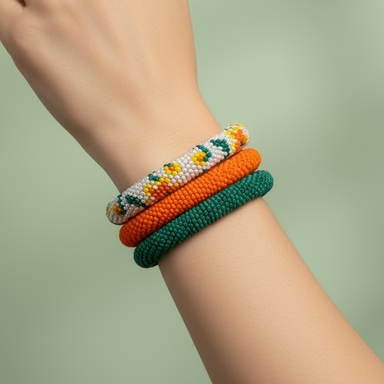 Hand wearing three colorful bracelets on a light green background - Beadzy