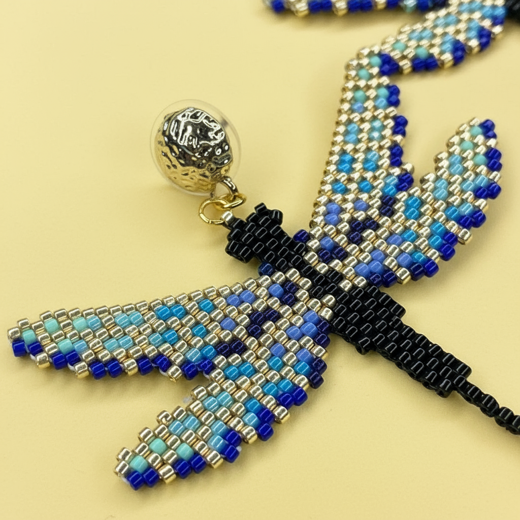 Beaded butterfly earring with blue, black, and gold colors on a yellow background - Beadzy