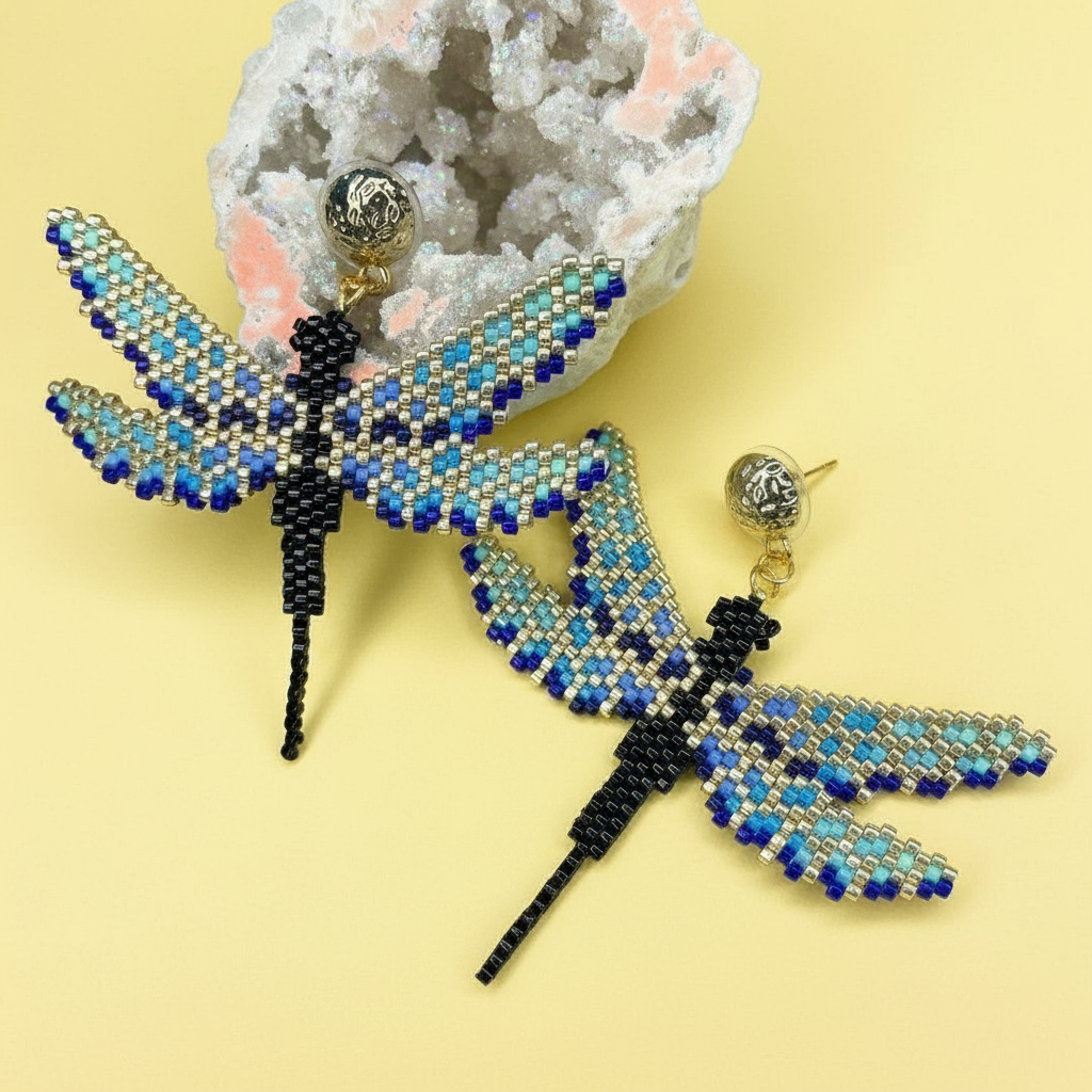Beaded blue and gold dragonfly earrings on a yellow background with a crystal geode - Beadzy