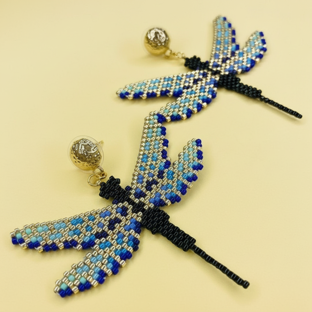 Beaded blue and gold dragonfly earrings on a yellow background - Beadzy