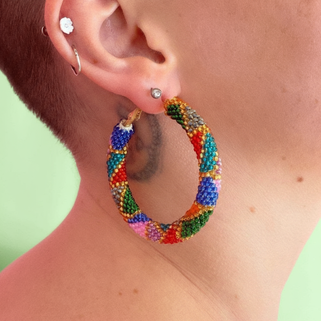 Colorful beaded hoop earring worn by a person with a green background - Beadzy