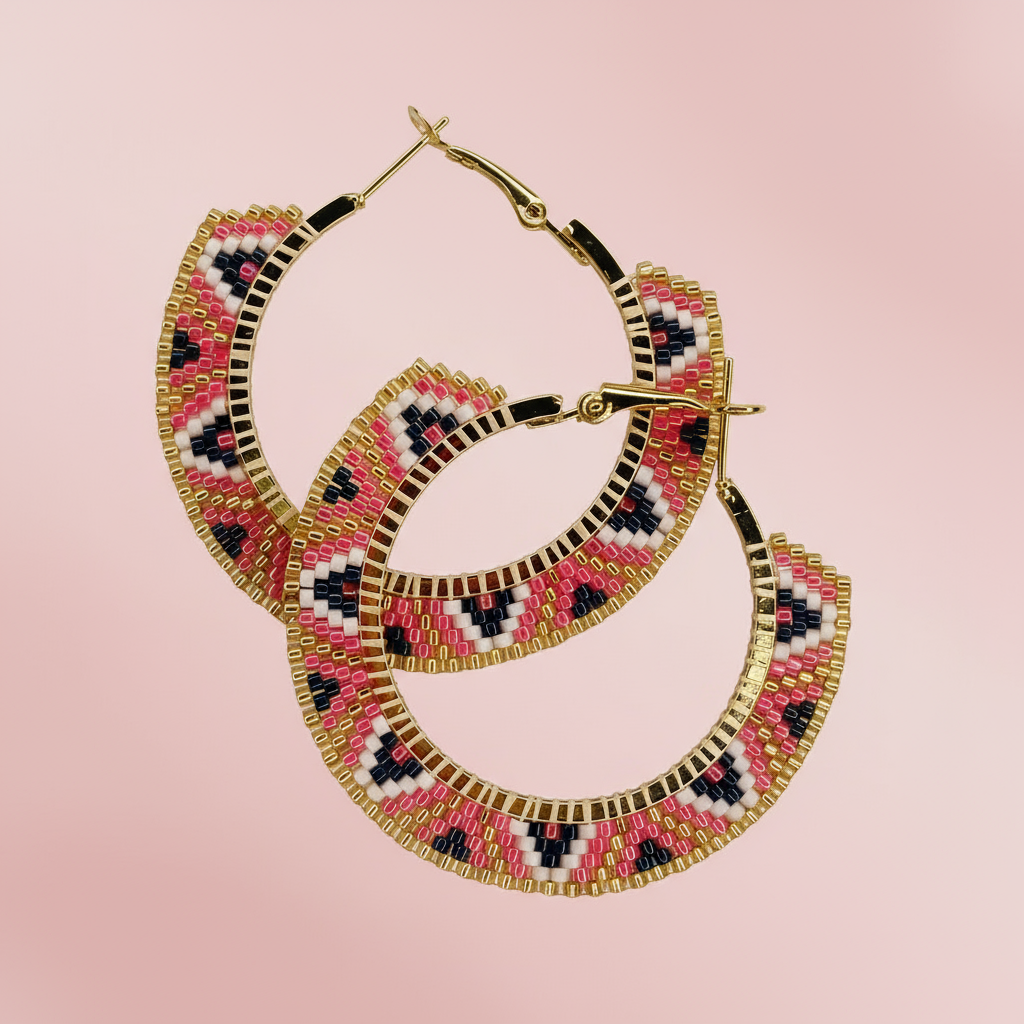 Beaded hoop earrings with pink, black, and gold pattern on a pink background - Beadzy