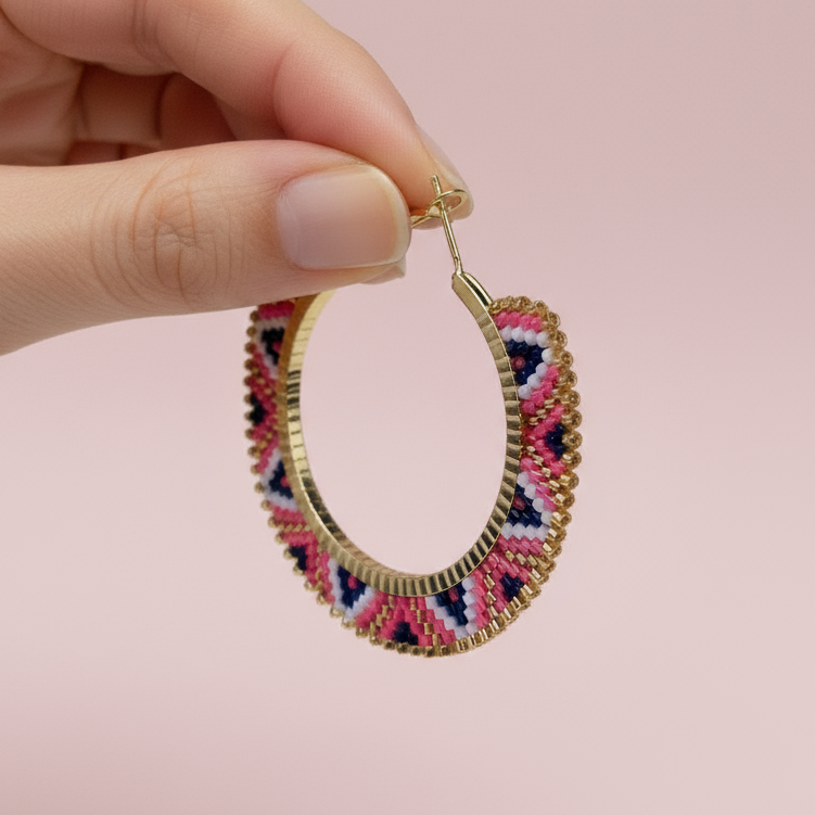 Pair of colorful beaded hoop earrings on a light pink background - Beadzy