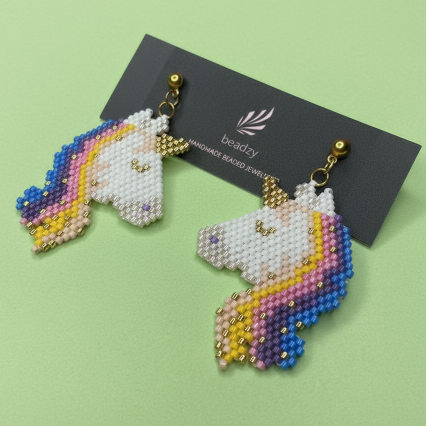 Unicorn-shaped beaded earrings on a green background with 'Beadzy' branding card. - Beadzy