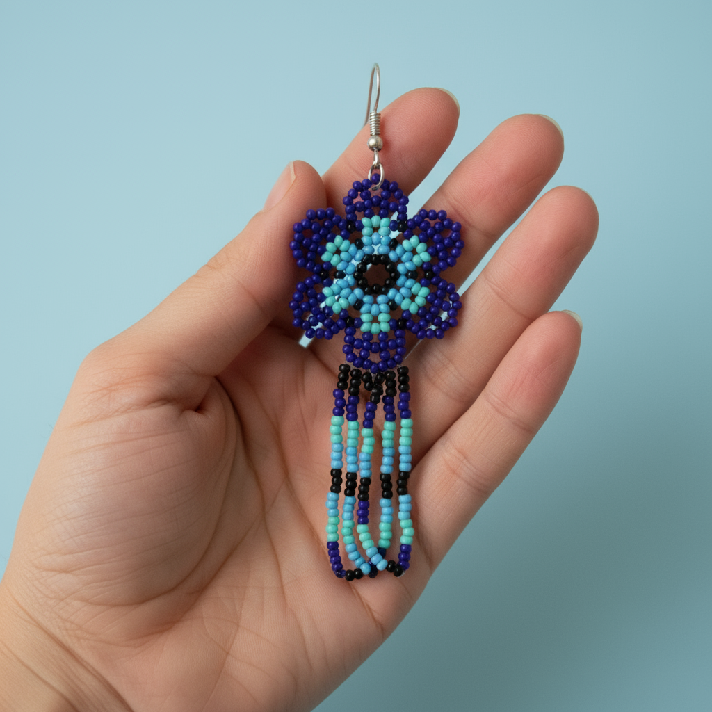 Beaded blue flower earring held in a hand against a light blue background - Beadzy