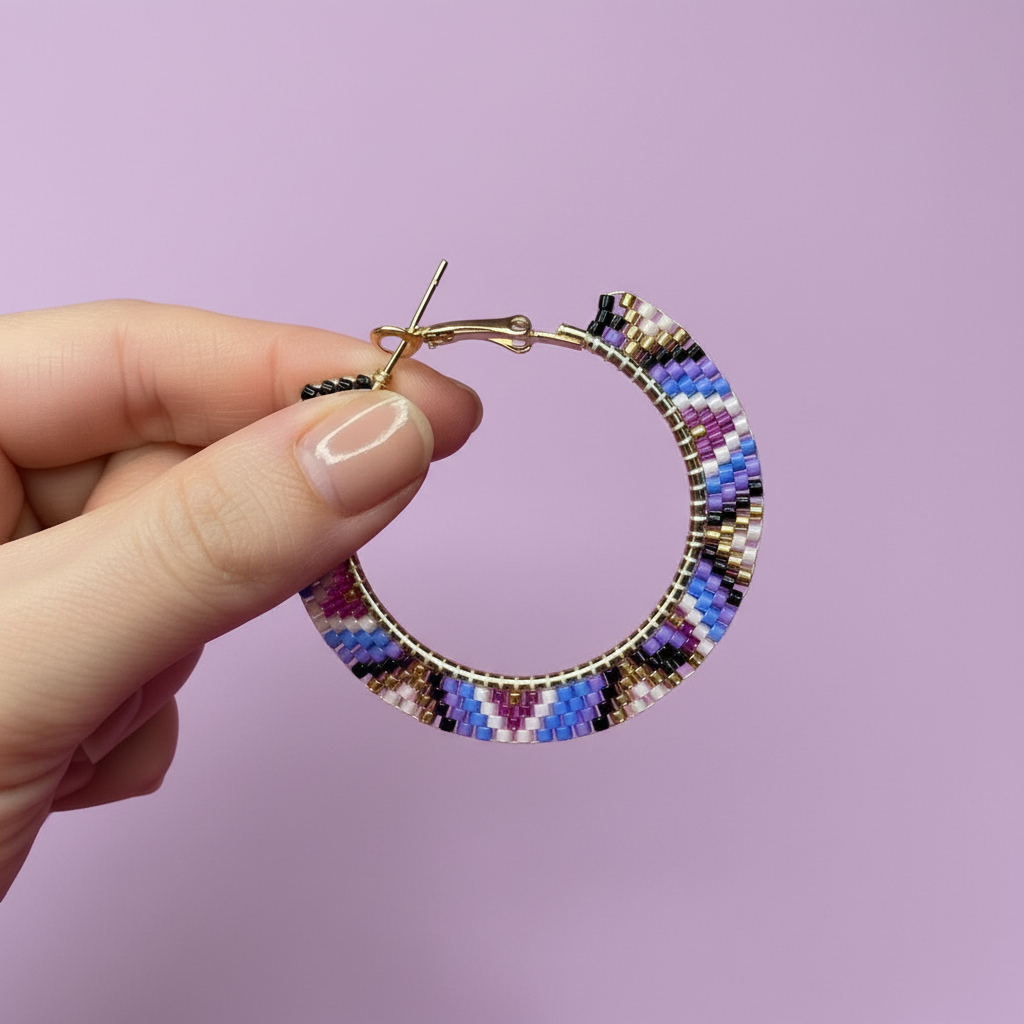 Multicolored beaded hoop earring held by a hand against a purple background - Beadzy