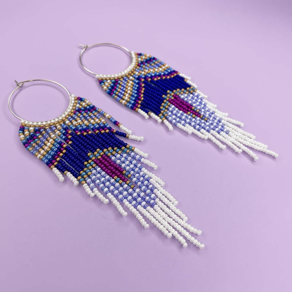 Beaded earrings with blue, purple, and white fringes on a light purple background - Beadzy
