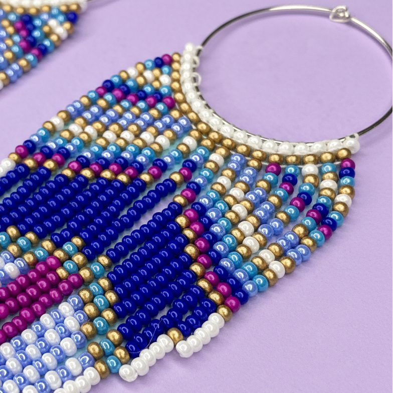 Beaded earrings with blue, purple, and gold colors on a purple background - Beadzy