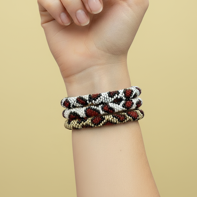 Hand wearing three leopard pattern beaded bracelets on a beige background - Beadzy