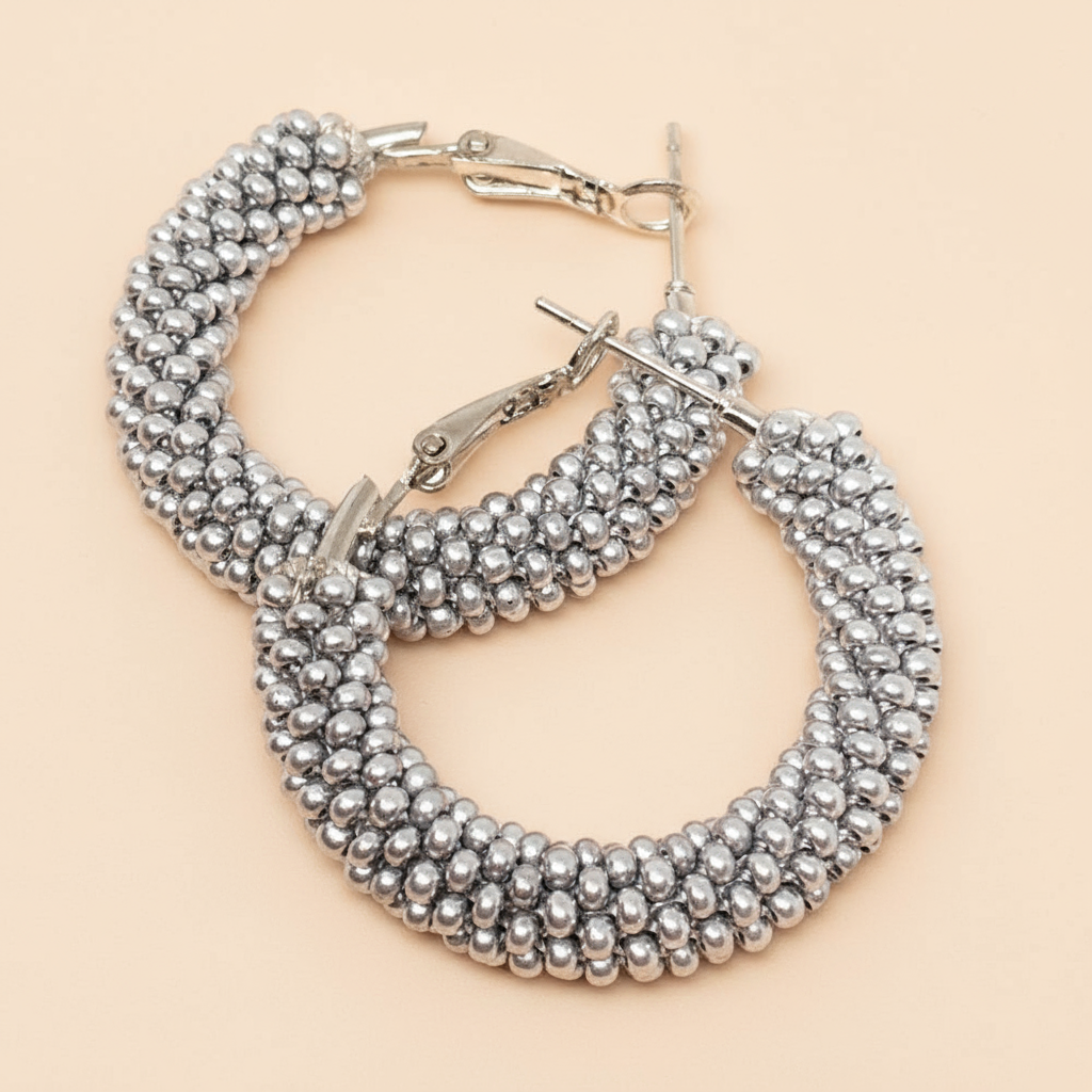Pair of silver beaded hoop earrings on a beige background - Beadzy