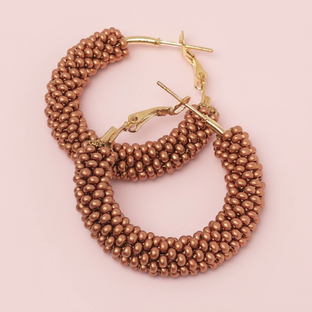 Pair of gold hoop earrings with beaded design on a pink background - Beadzy