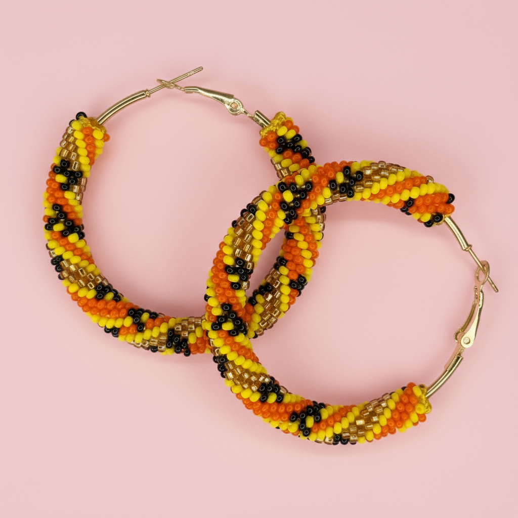 Beaded hoop earrings with orange, yellow, and black beads on a pink background - Beadzy