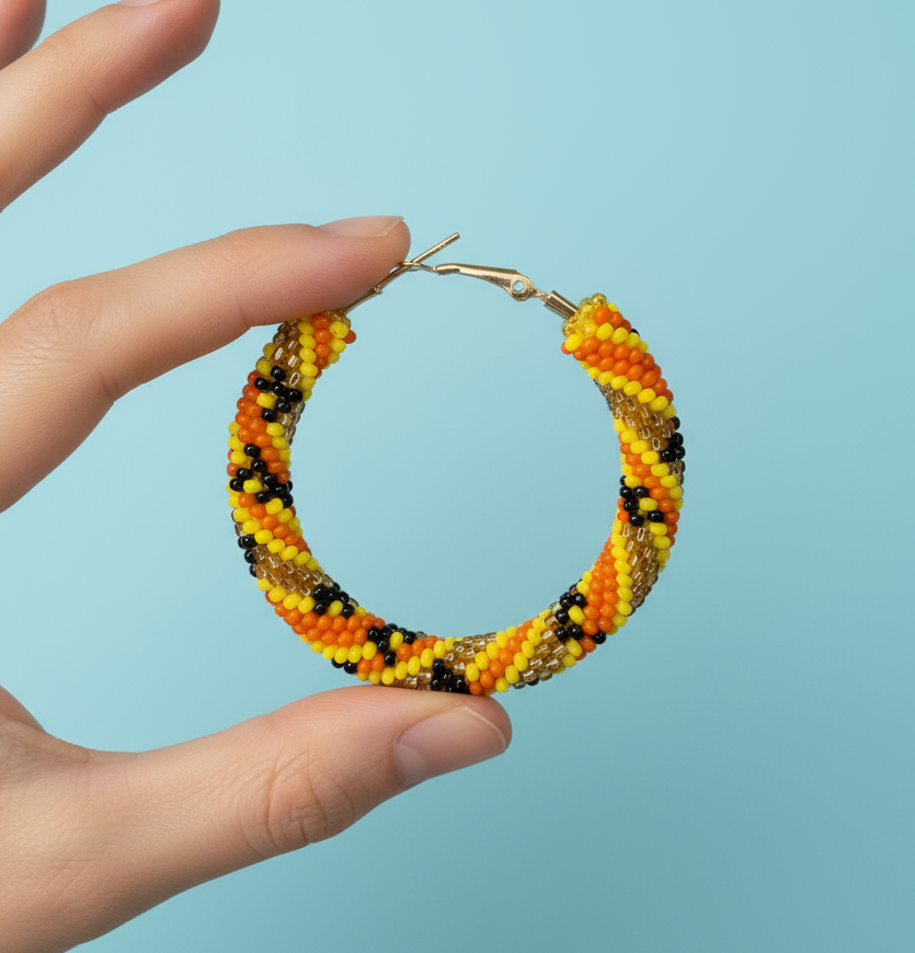 Hand holding a beaded hoop earring against a light blue background - Beadzy