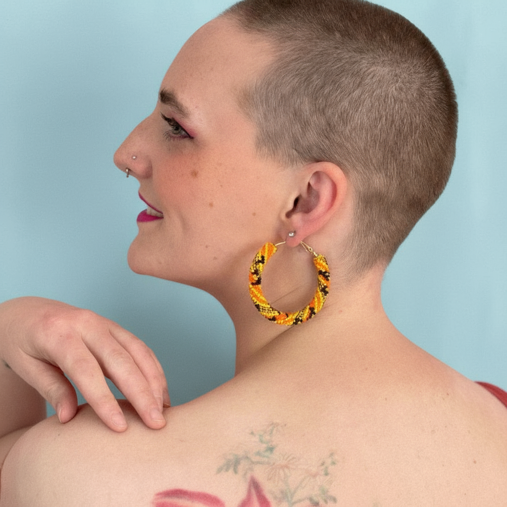 Person wearing a yellow large hoop earring with a blue background - Beadzy