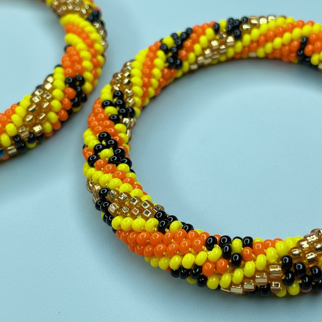 Close up Beaded hoop earrings with orange, yellow, and black pattern on a light blue background - Beadzy