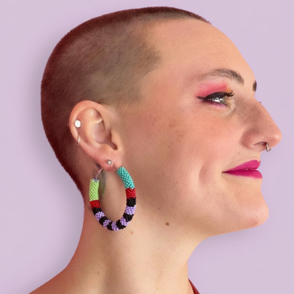 Woman wearing colorful hoop earrings against a light purple background - Beadzy