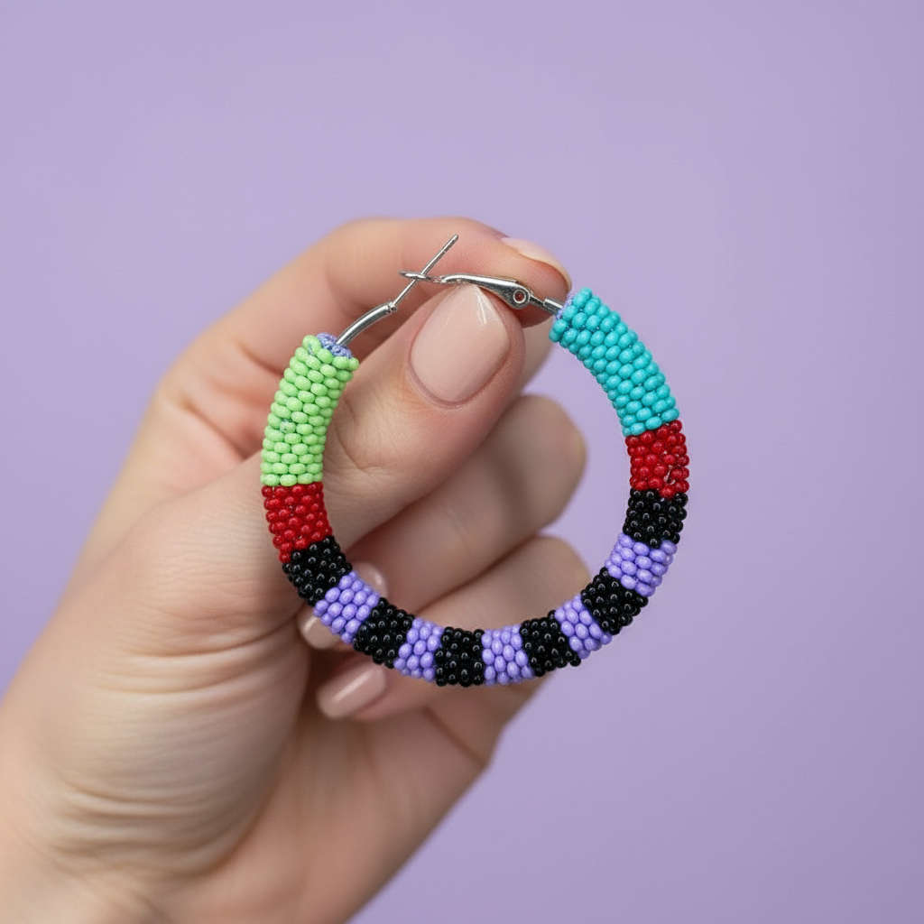 Colorful beaded hoop earrings held by a hand against a purple background - Beadzy