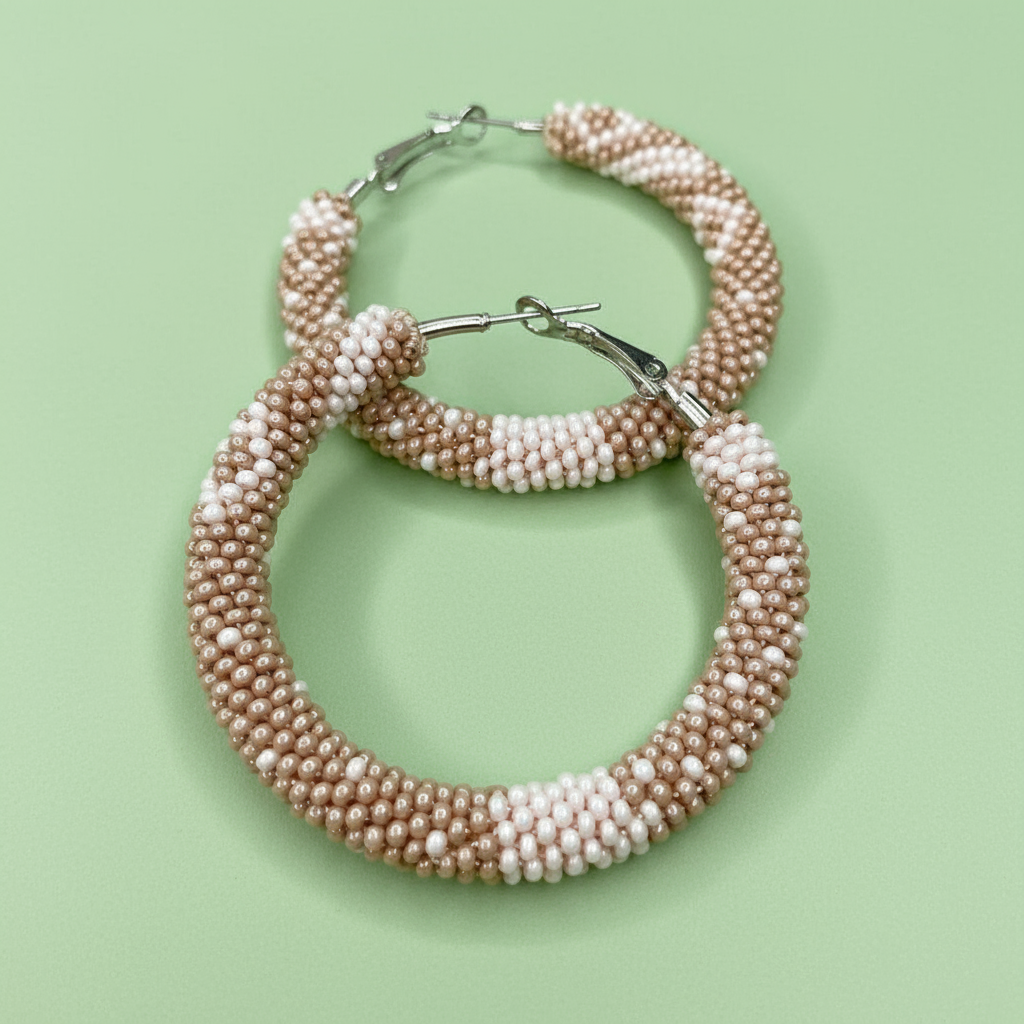 Pair of pink and beige hoop earrings on a light green background - Beadzy
