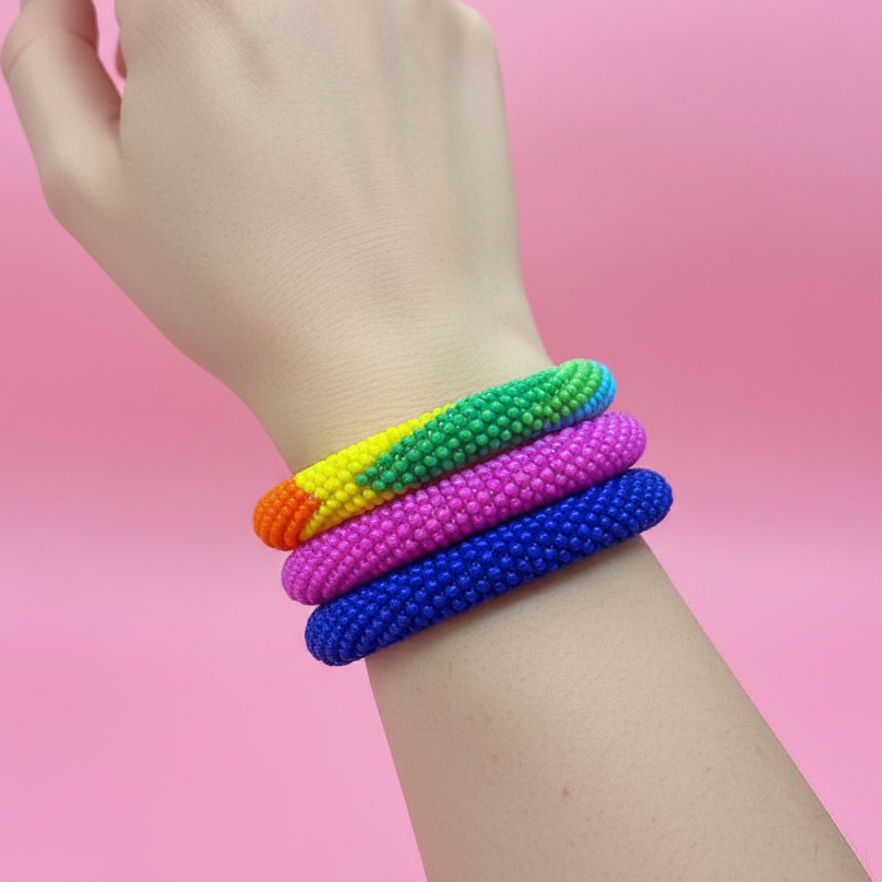 Hand wearing colorful beaded bracelets on a pink background