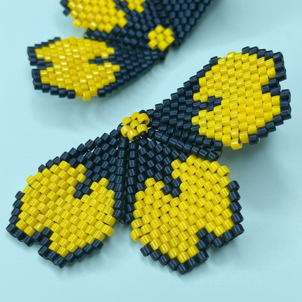 Beaded flower earrings with yellow and black beads on a light blue background - Beadzy