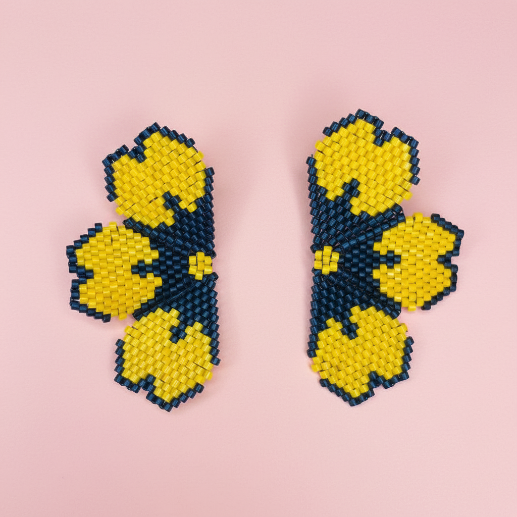 Pair of beaded earrings with yellow and black floral patterns on a pink background - Beadzy