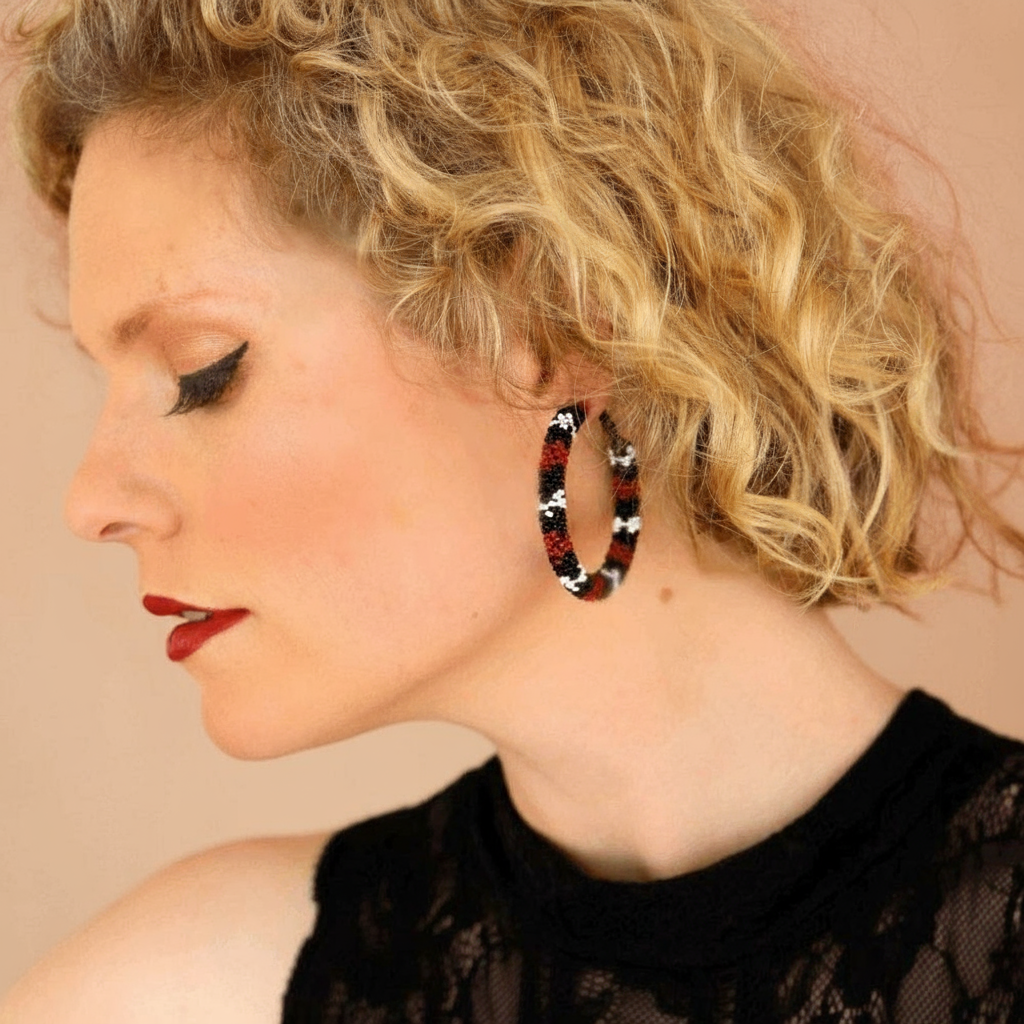 Woman wearing a large hoop earring with a snake design against a beige background - Beadzy