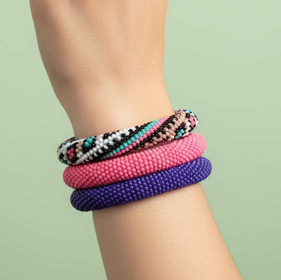 Stack of colorful beaded rope bracelets on a wrist against a light green background - Beadzy