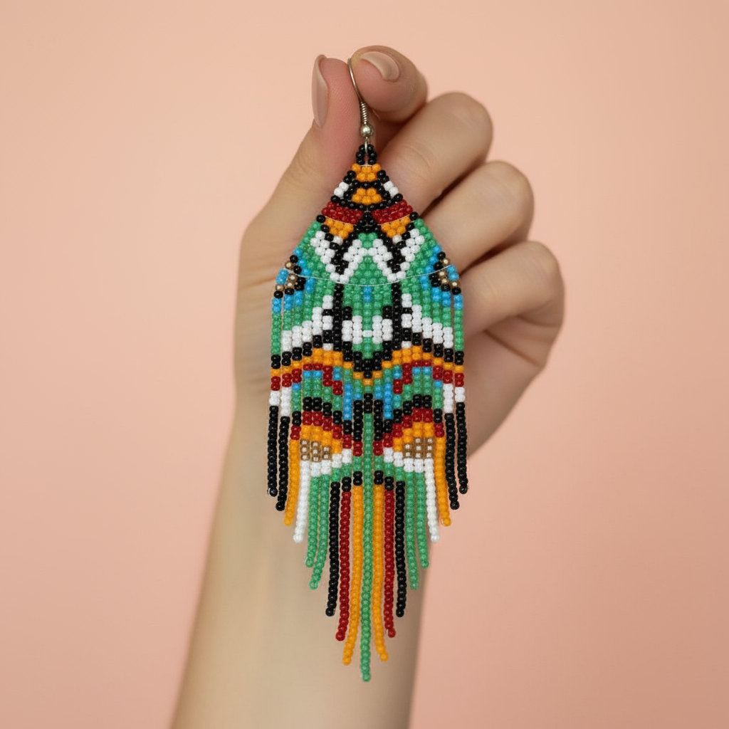 Colorful tribal beaded tassel earrings held by a hand against a beige background - Beadzy