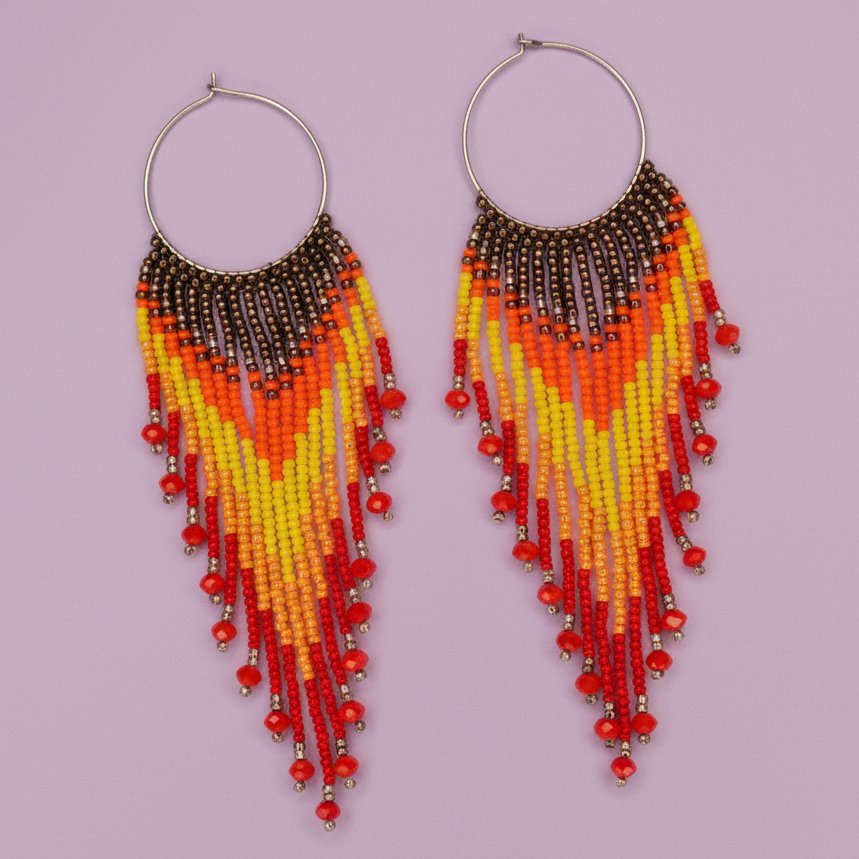Beaded earrings with red, orange, and yellow pattern on a light purple background - Beadzy