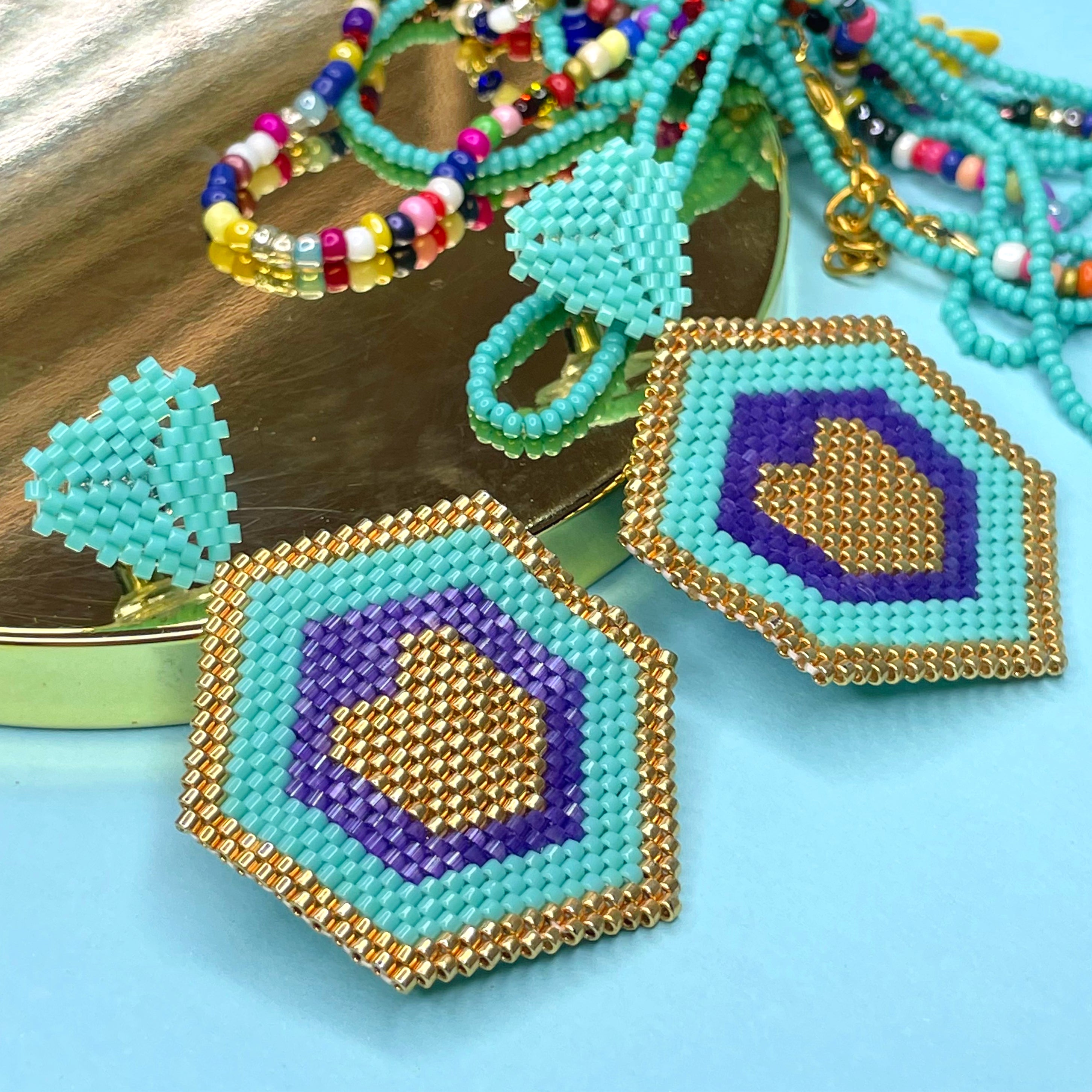 Hexagonal beaded earrings with blue, gold, and purple on a blue background - Beadzy