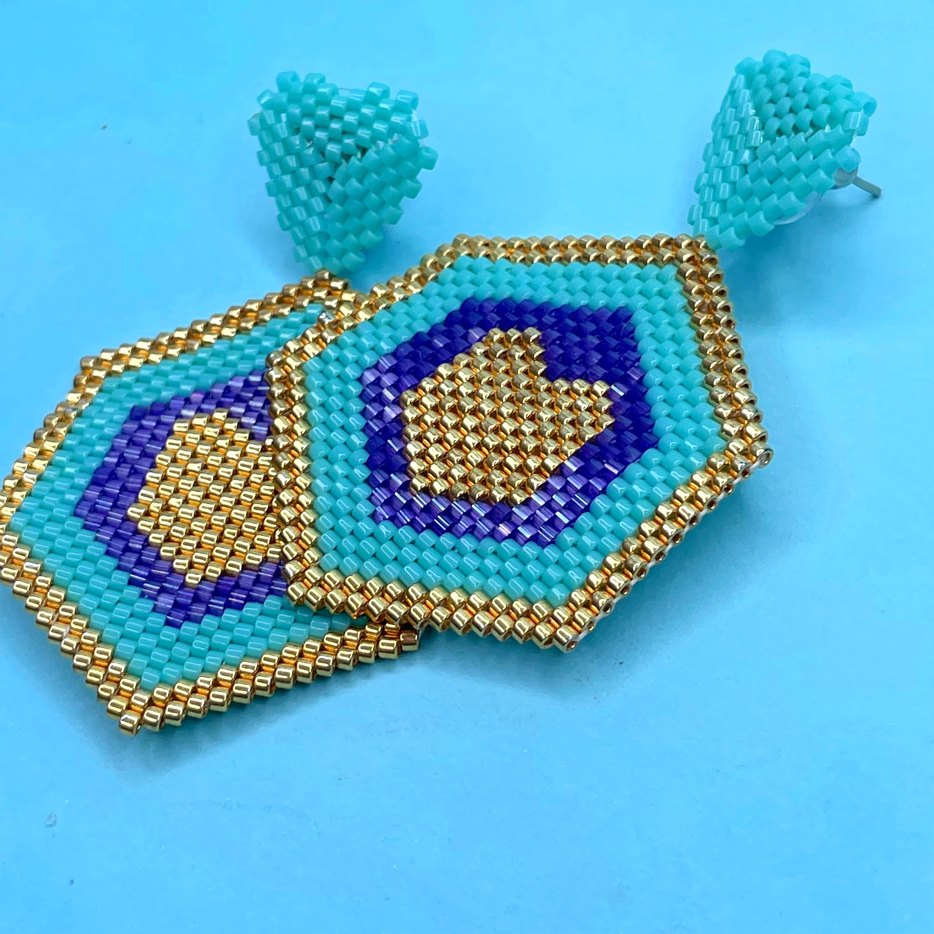 Hexagonal beaded earrings with blue, gold, and purple on a blue background - Beadzy