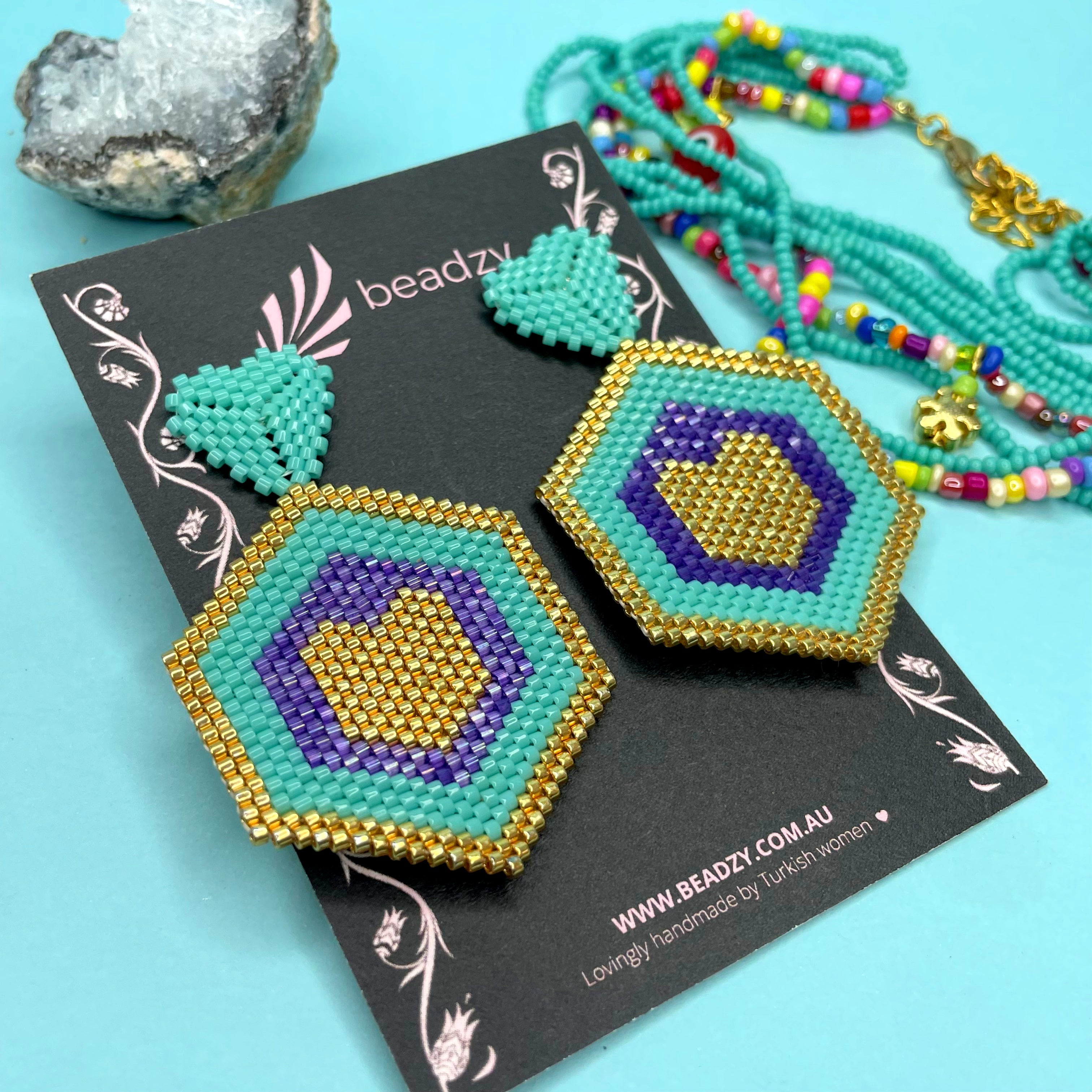 Hexagonal beaded earrings with blue, gold, and purple on a blue background - Beadzy