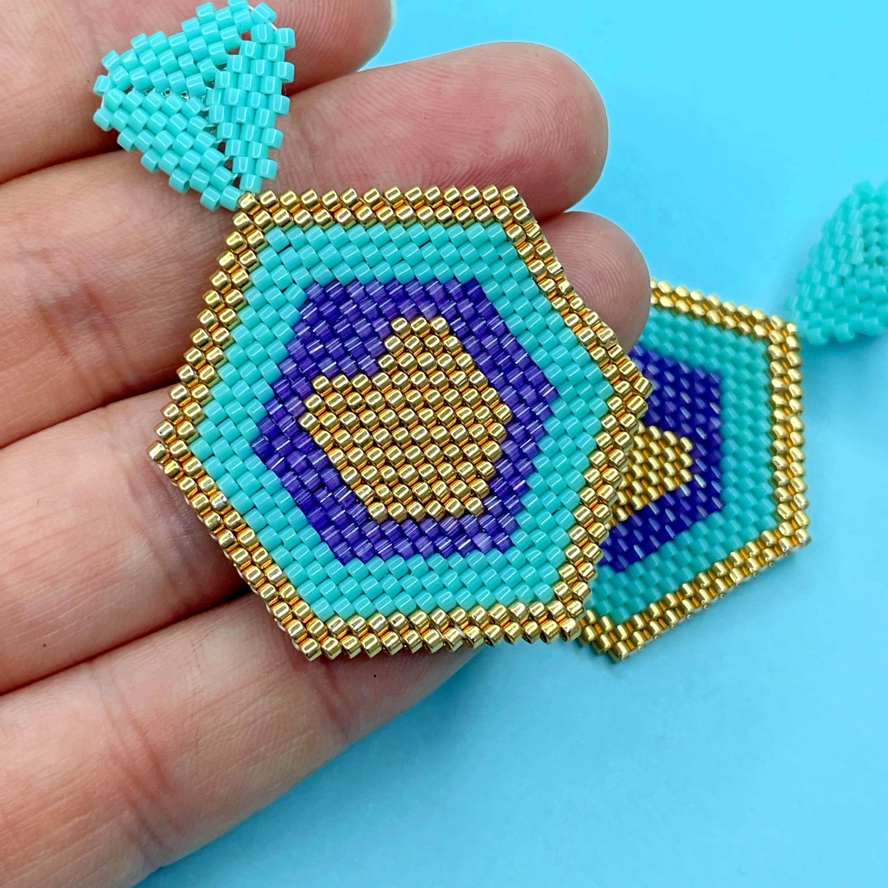 Hexagonal beaded earrings with blue, gold, and purple on a blue background - Beadzy